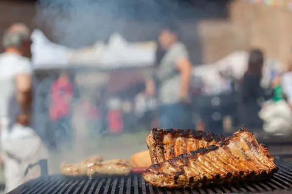 Outdoor community barbecue with grilled ribs over smoky charcoal