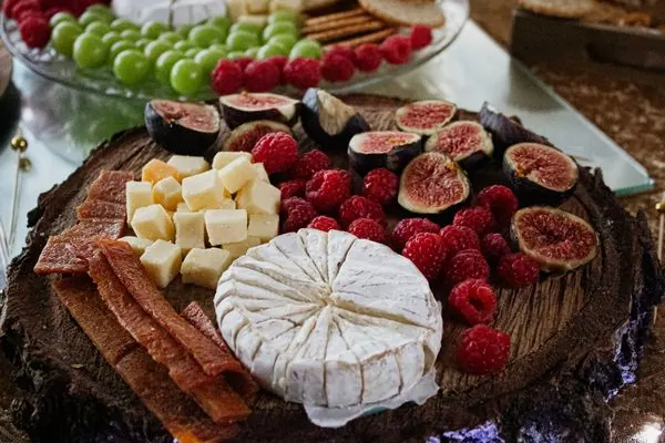 Artisan cheese and fruit board with brie, figs, raspberries, and grapes