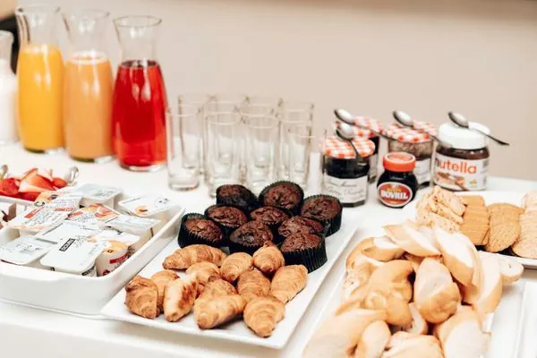Breakfast catering spread with croissants, muffins, and fresh juice pitchers