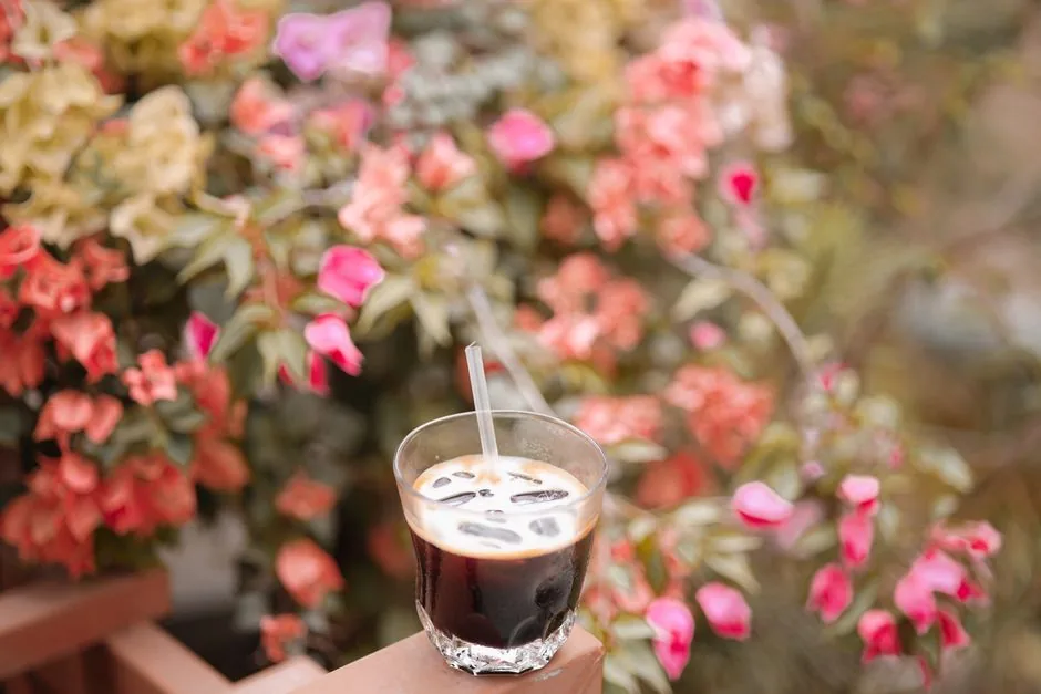 Iced coffee in a glass set against a coastal backdrop on a warm summer day
