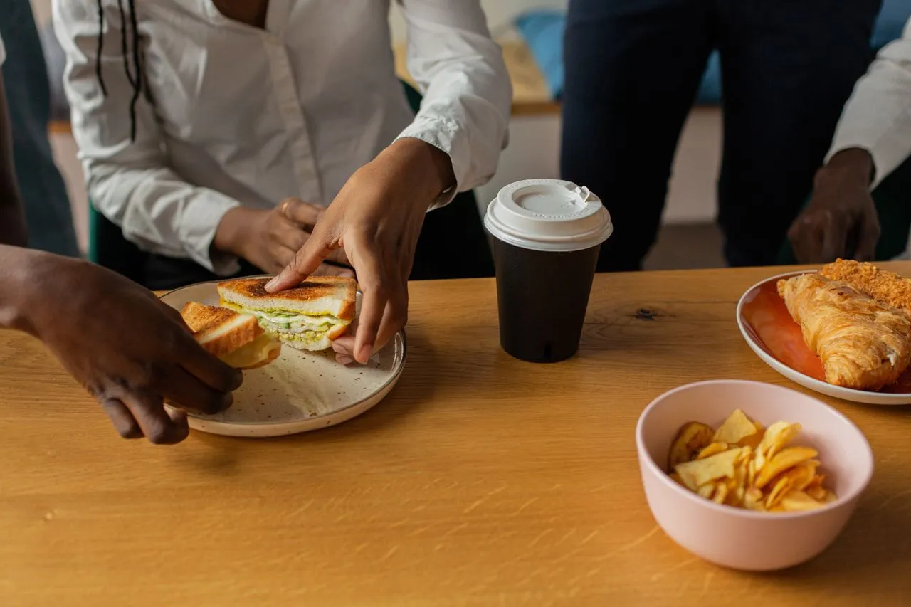 Professional breakfast spread with coffee, sandwiches, and pastries arranged for an office team meeting